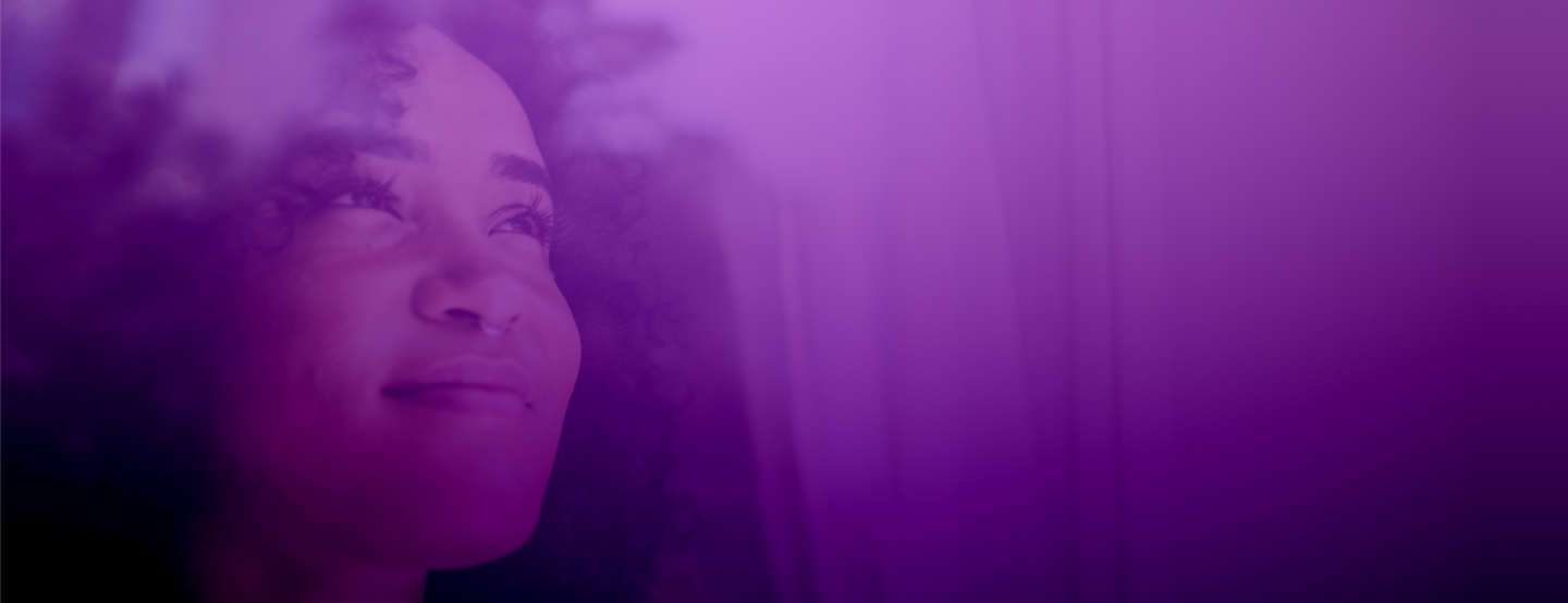 Femme atteinte de lupus sourit doucement en regardant par la fenêtre, symbole d’espoir et de force