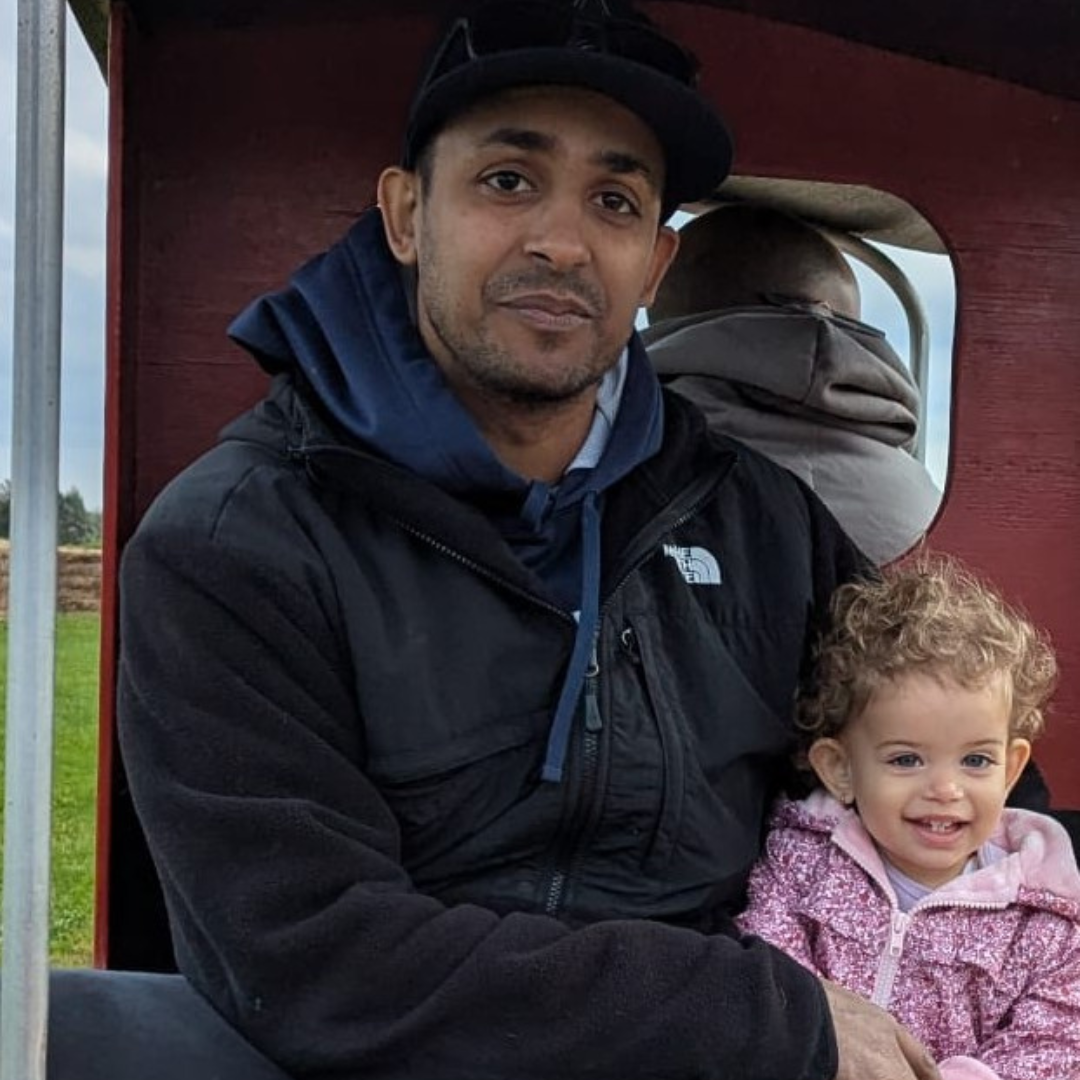 Nathan S – Fatherhood and Life with Lupus Nathan S smiling with his daughter inside a trailer, surrounded by nature, showing joy and resilience while living with lupus
