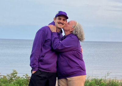 Elliot Saucier smiling as his mother, Lise Bouchard, kisses him on the cheek after completing his 230 km run for lupus awareness.