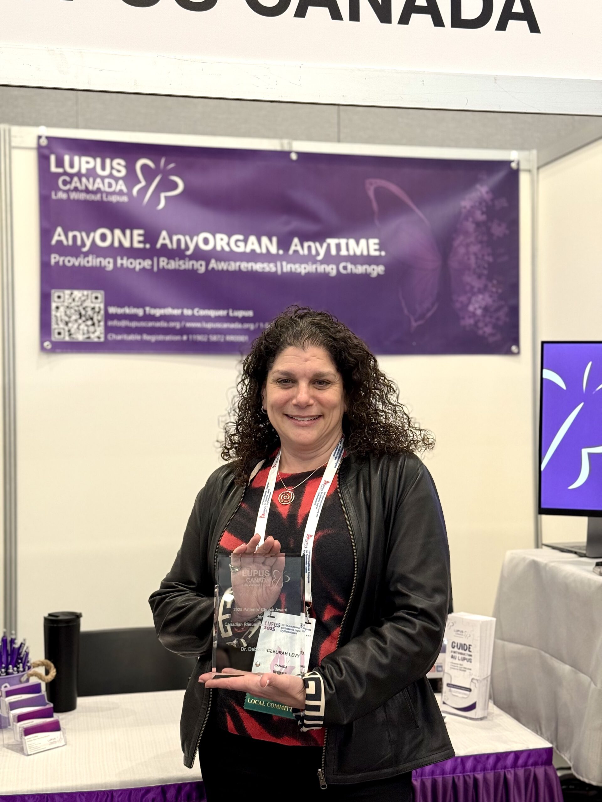 Dr. Deborah Levy holds her Patients’ Choice Award while standing at the Lupus Canada booth.