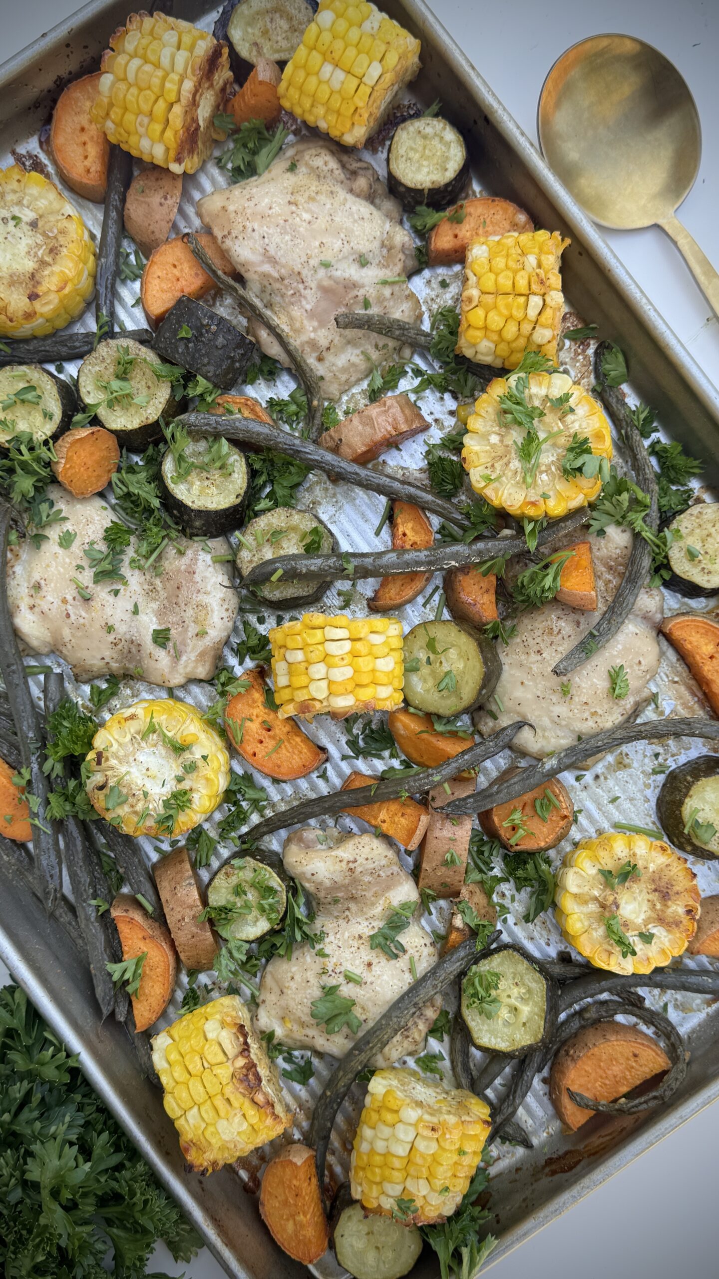 Repas de poulet à la poêle avec maïs rôti, patates douces, courgettes, haricots verts et cuisses de poulet à la moutarde à l’érable, garnies d’herbes fraîches.