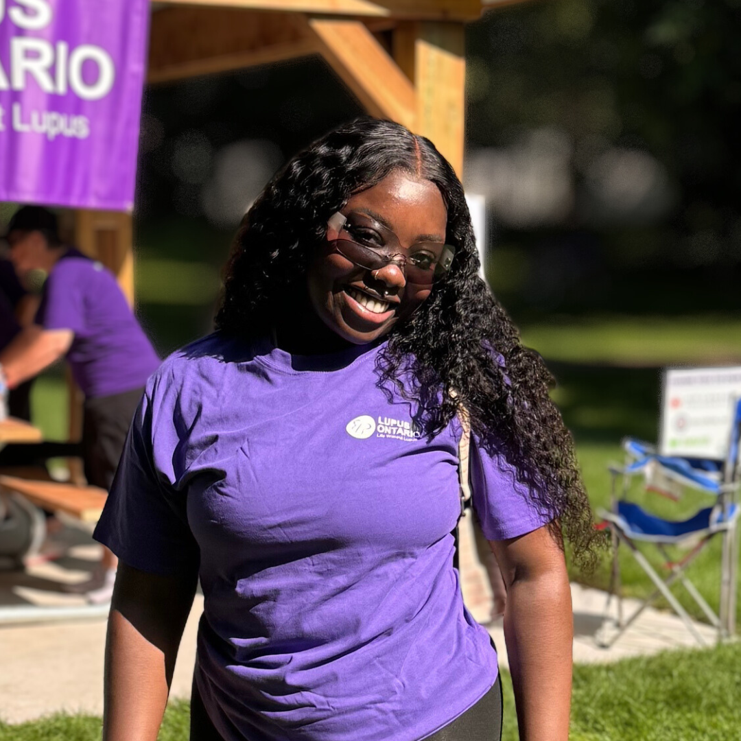 Photo of Jahmeila Moore, Lupus Canada Scholarship Winner, wearing a purple Lupus Ontario T-shirt outdoors.