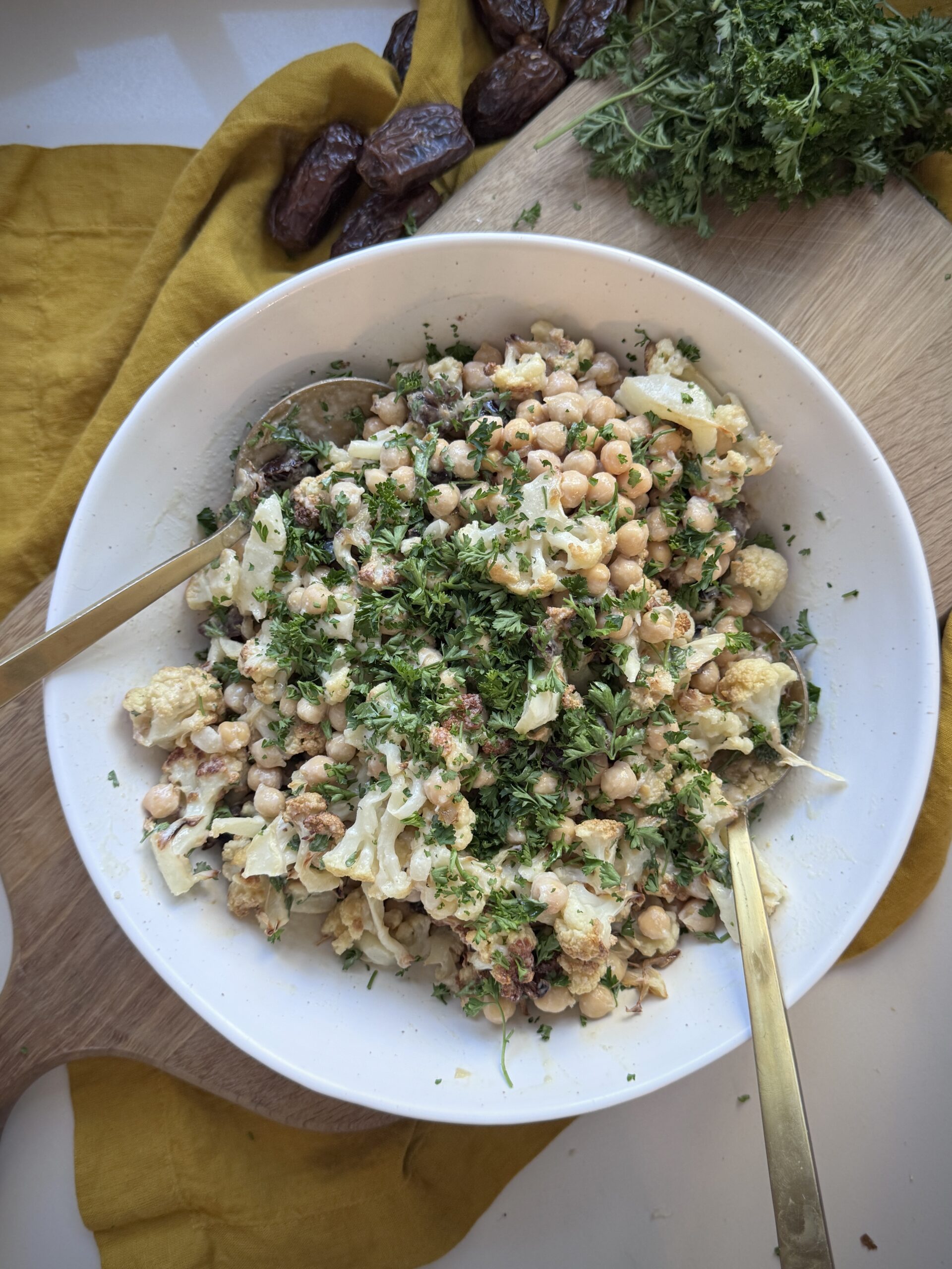 Bowl of roasted cauliflower chickpea salad with parsley and lemon-tahini dressing.