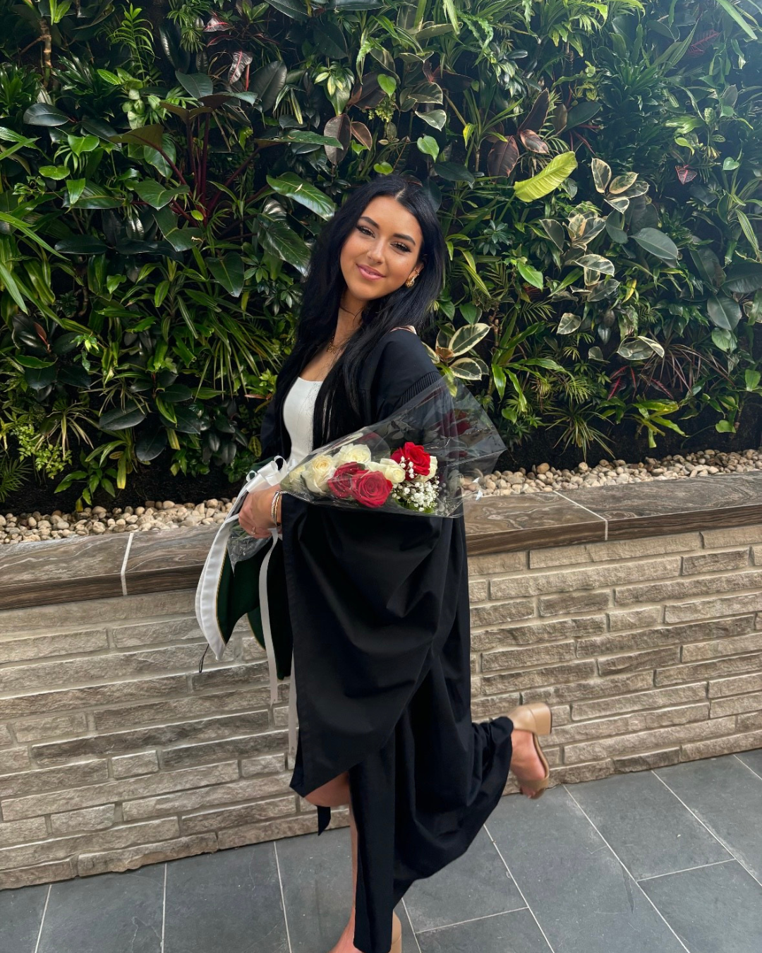 Un récipiendaire d’une bourse d’études de Lupus Canada en robe de graduation tenant des fleurs, représentant l’éducation et l’autonomisation à travers 10 façons de donner.