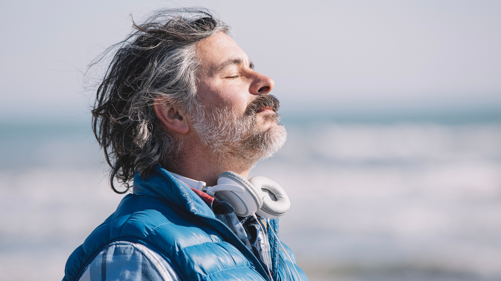 Man standing outdoors with eyes closed, breathing calmly near the ocean, used on a hepatitis B vaccine lupus information page to symbolize wellness and prevention.
