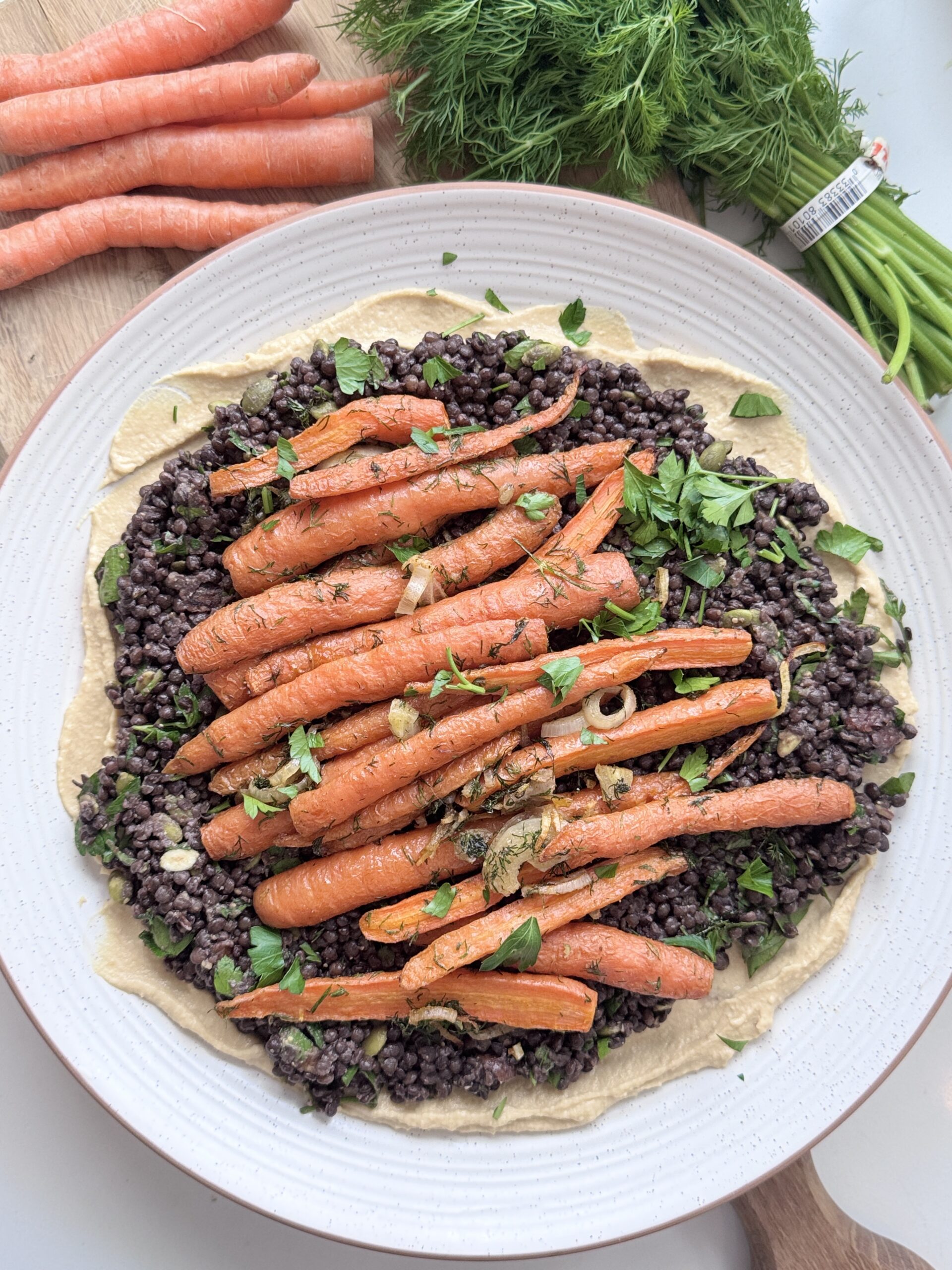 Carottes rôties avec lentilles sur un plateau avec herbes et houmous, une recette riche en nutriments et respectueuse du lupus.