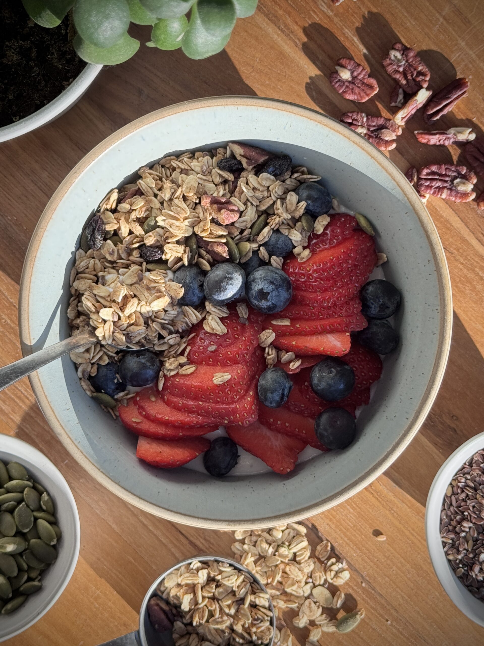Granola sans huile servi avec yaourt, fraises fraîches, myrtilles et graines dans un bol