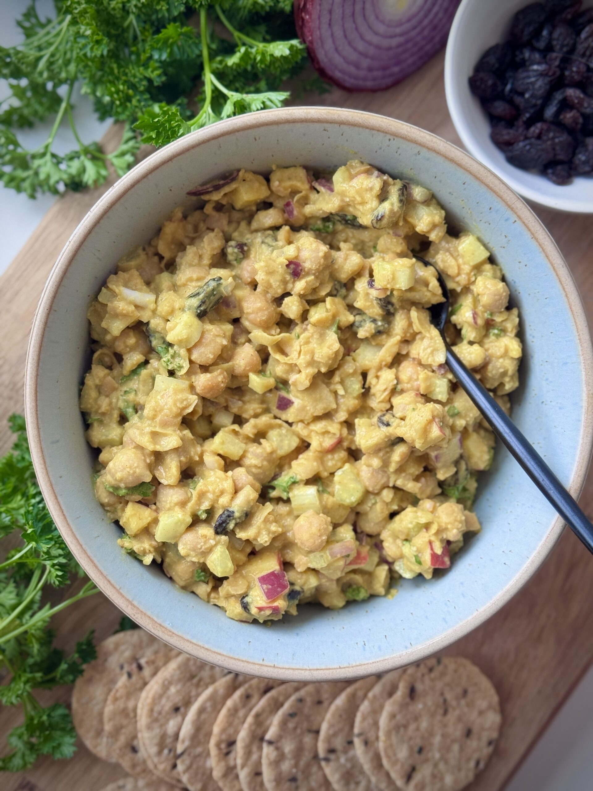 Anti-inflammatory chickpea salad made with turmeric, curry spices, and tahini dressing served in a bowl with crackers