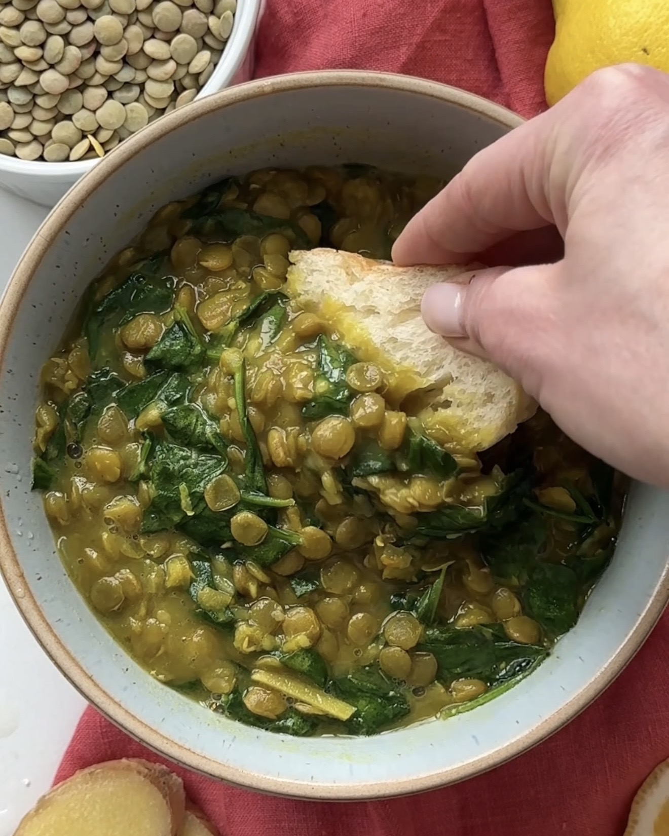 lemon ginger lentil soup recipe with spinach and turmeric in a bowl with bread