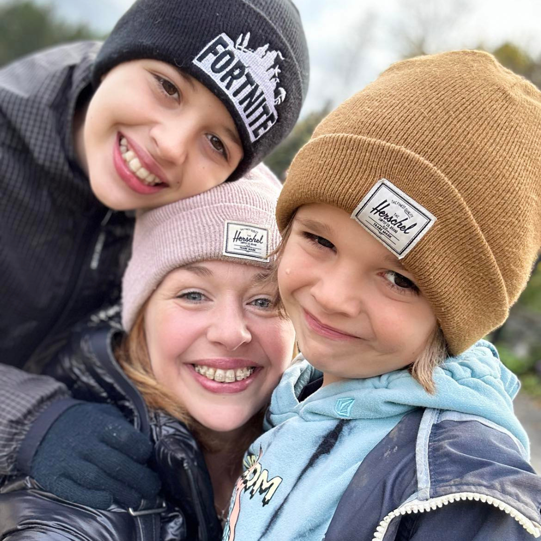 Danielle souriant avec deux enfants à l’extérieur, représentant le soutien familial et vivant avec le lupus au Canada