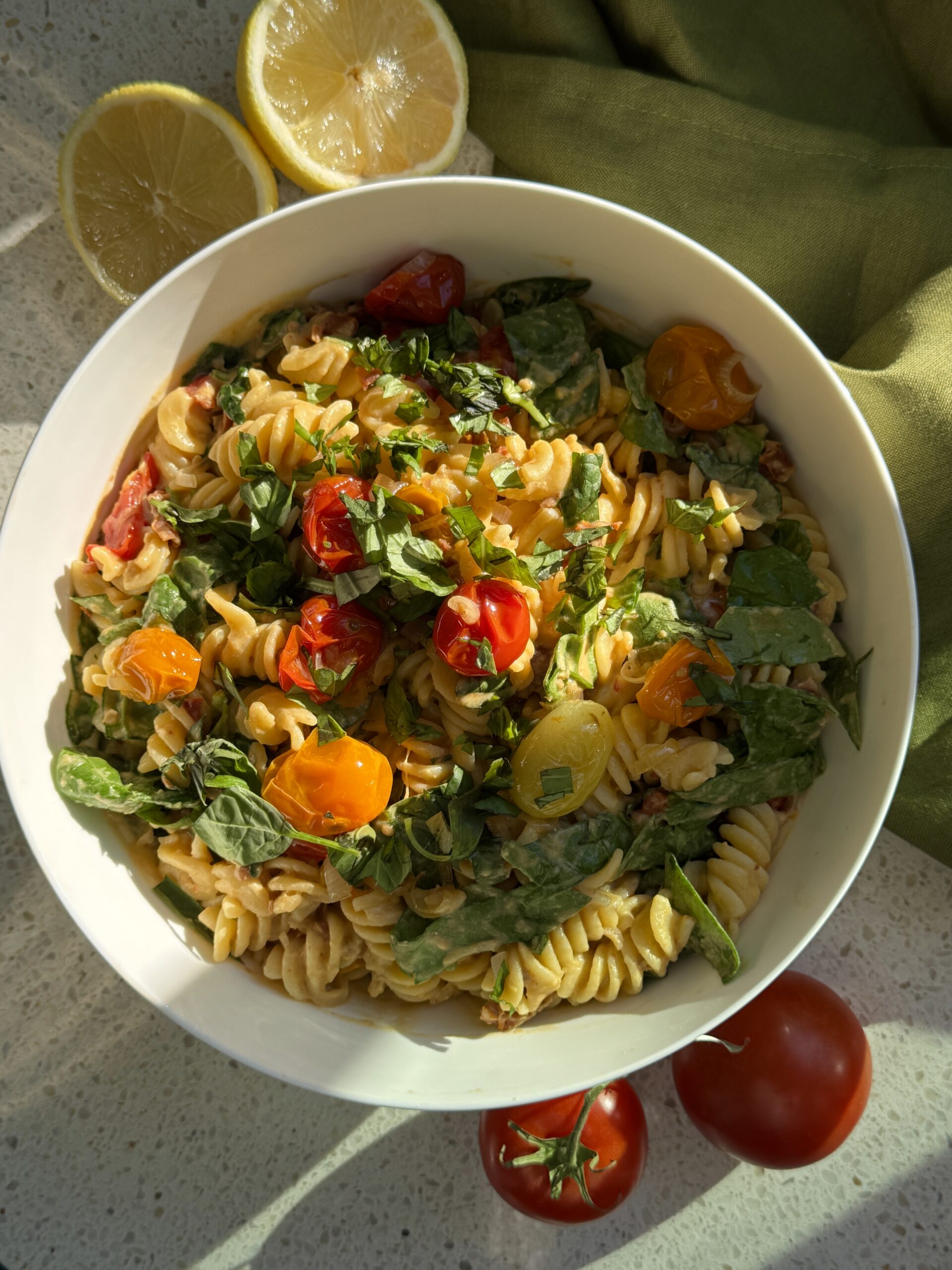 Hummus pasta recipe with roasted cherry tomatoes, spinach and fresh basil
