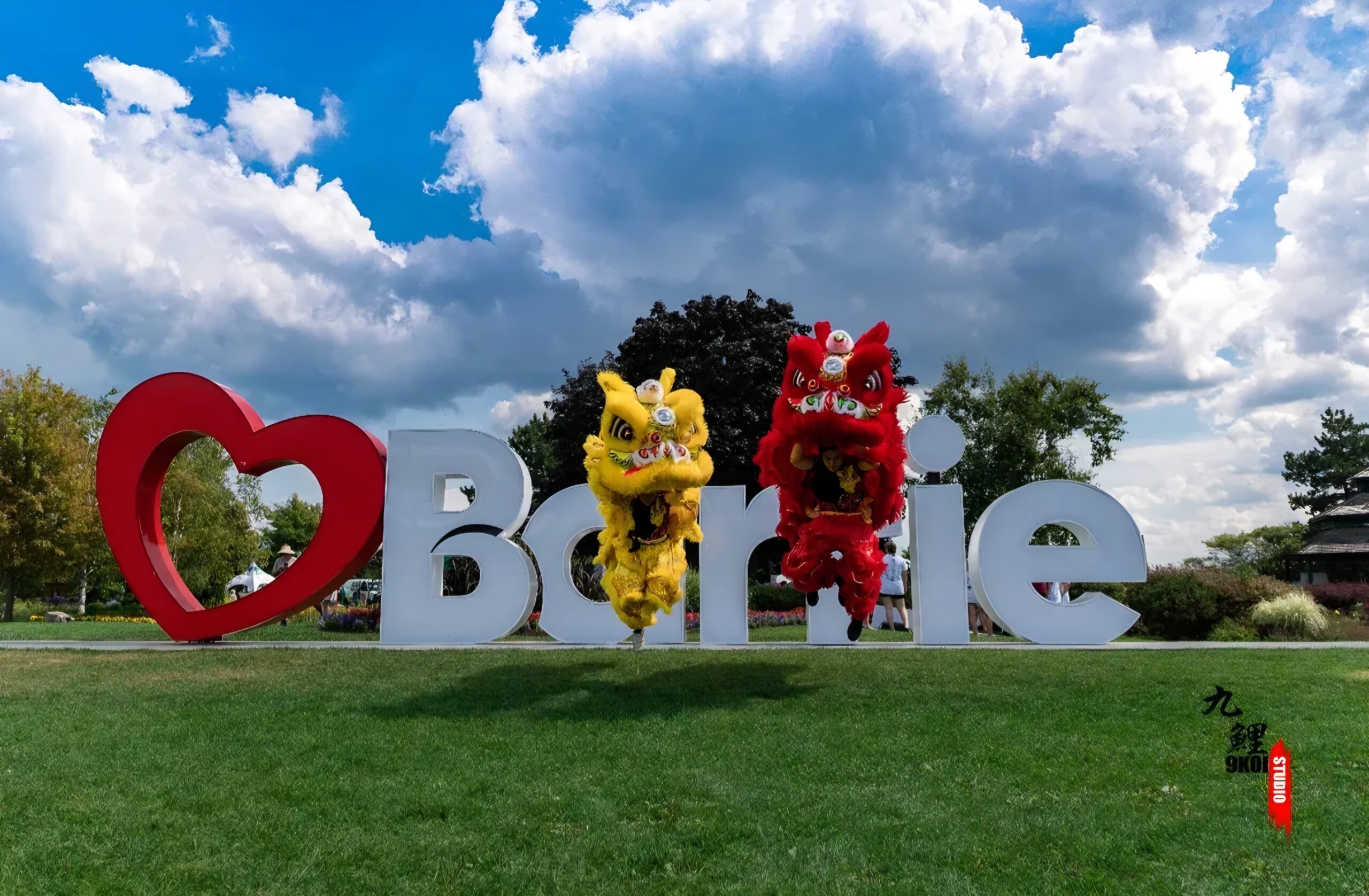 Des costumes de danse du lion chinois rouge et jaune se produisant en plein air devant l’enseigne Barrie en Ontario.