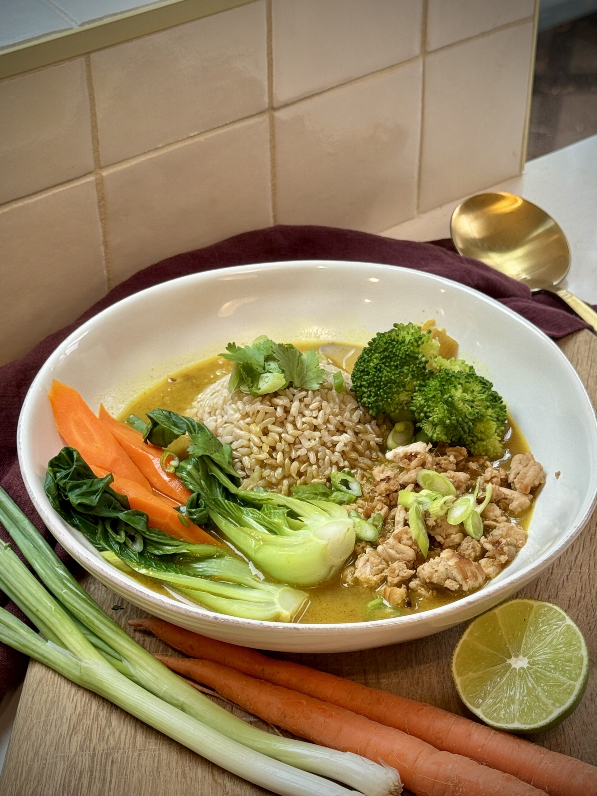 Ginger Turmeric Chicken Bowl with ground chicken, brown rice, broccoli, carrots, bok choy, and fresh cilantro in a golden coconut broth.