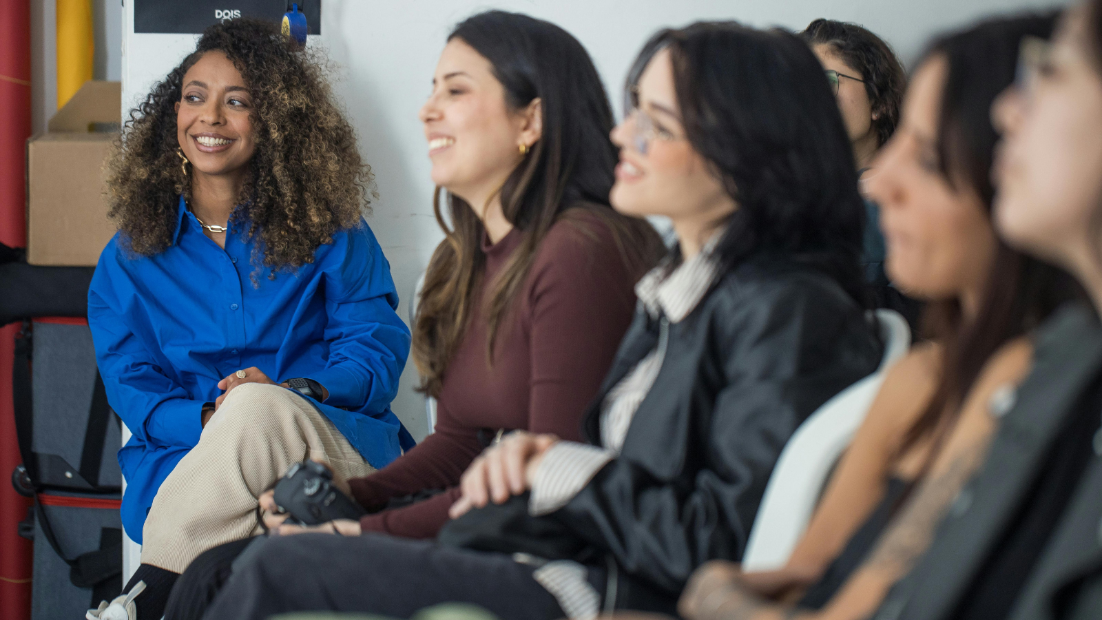 Group of women smiling and listening during a discussion, representing community engagement and advocacy.